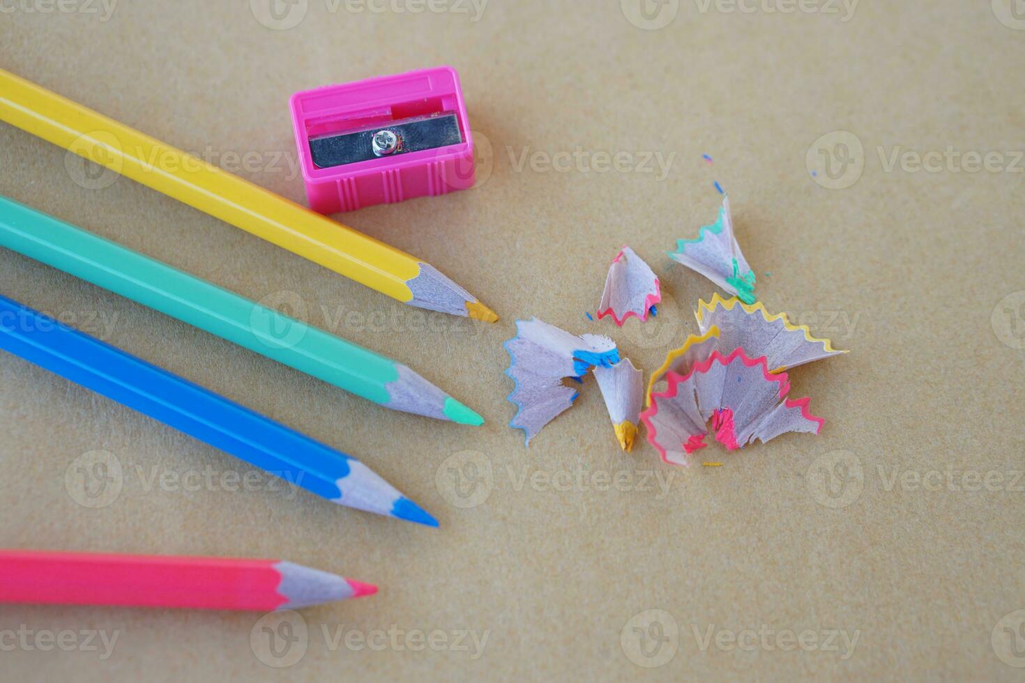 Wooden colorful pencil scraps, pencils and sharpener on brown background. Concept, education materials for creative drawing, art subject, support learning of autistic disorder children photo