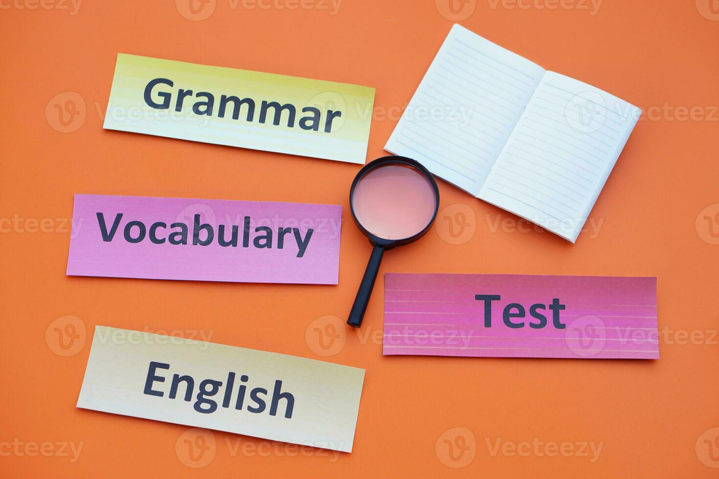 Paper word cards with text Vocabulary, English, Grammar, Test. Magnifying glass. Orange background. Concept. Education material.Teaching aid. Learning language. photo