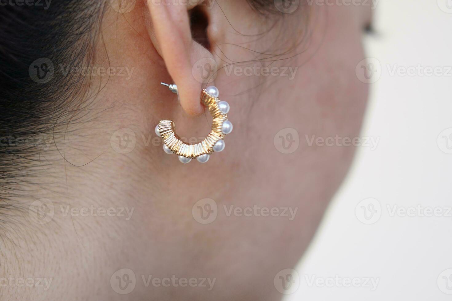 Close up fashionable pearl earring, pendant on woman's ear. Concept, beauty and fashion accessory to decorate on body part. Jewelry and Femininity. photo
