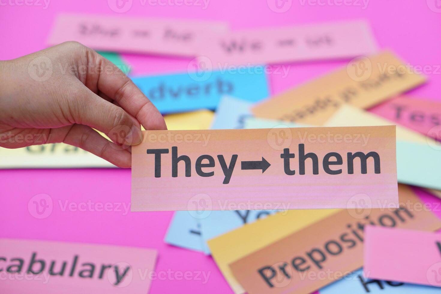 Close up hand hold pink wordcard with text They - them. Concept, English language grammar teaching. Using word card to create for playing educational fun games. photo