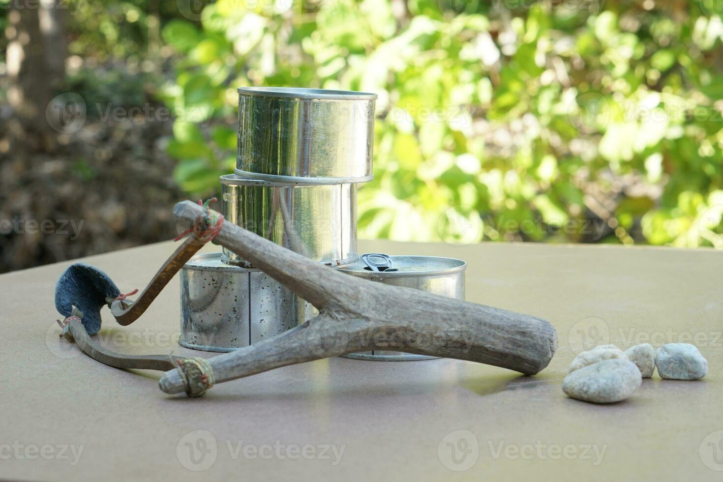 Slingshot, old cans and small rock bullets. Equipments for can shooting game. Concept ,Traditional game, Challenge, aim a catapult with stone bullet to cans and shoot. photo