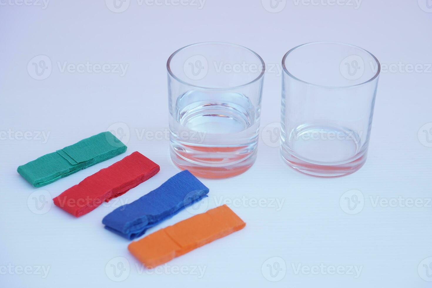 Two glass of water and colorful stripes paper. White background. Equipment prepared for doing science experiment about chromatography. Easy activity chemistry lesson for kid. photo