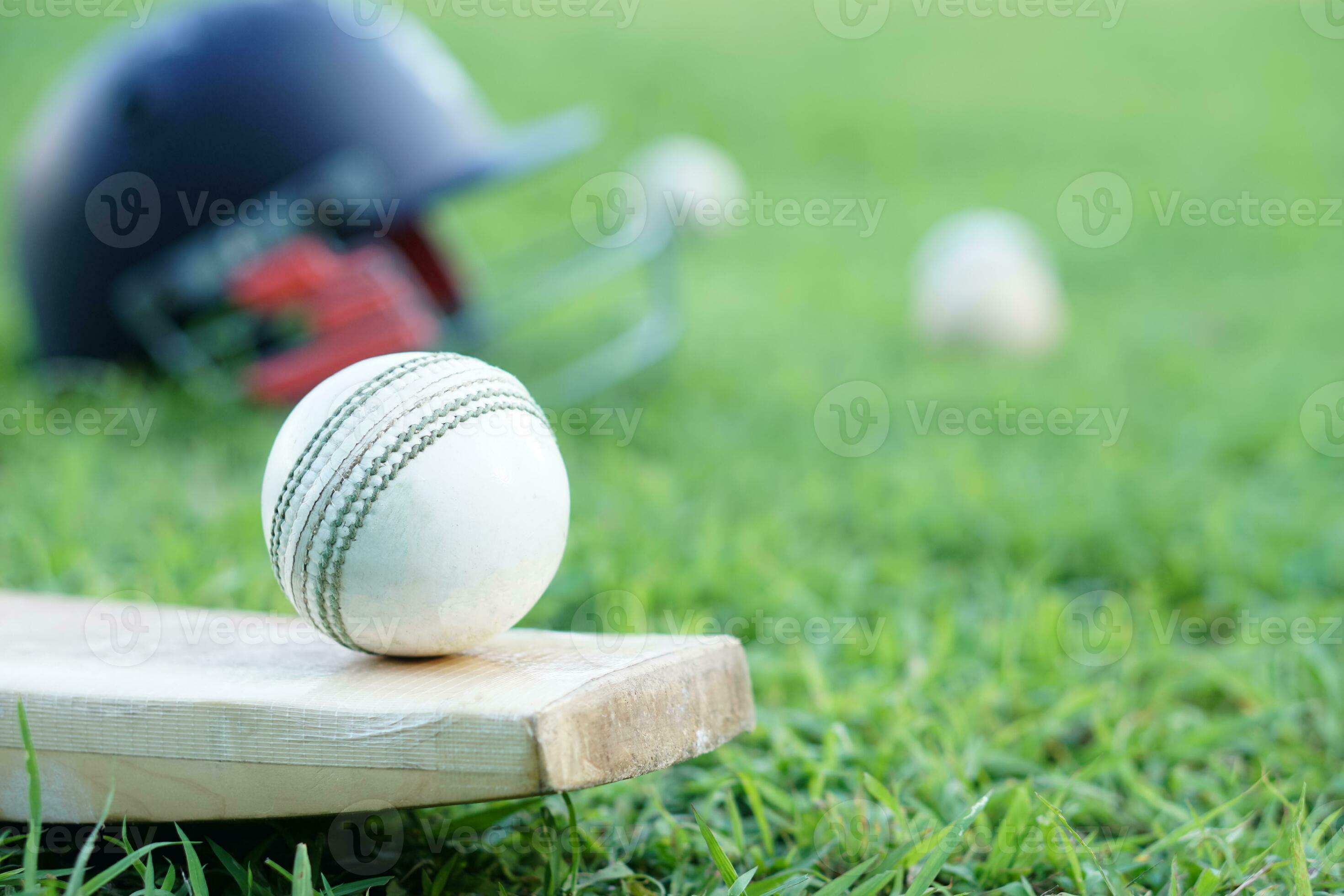 Cricket kits, helmet, cricket balls and bat on grass field. Concept