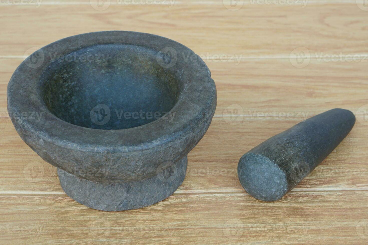Granite mortar and pestle on wooden background. Stone mortar is an important tool for Thai people to make curry paste. Every family will have a mortar and pestle in the kitchen. photo