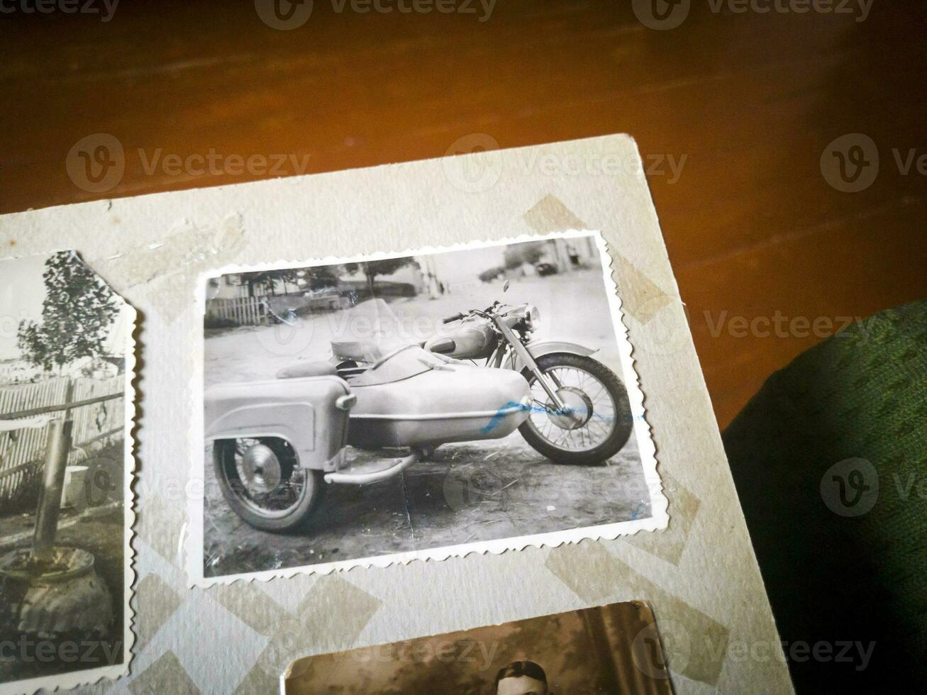 Close up shot of an old black and white picture of a vintage motorcycle in a photo album. Antique