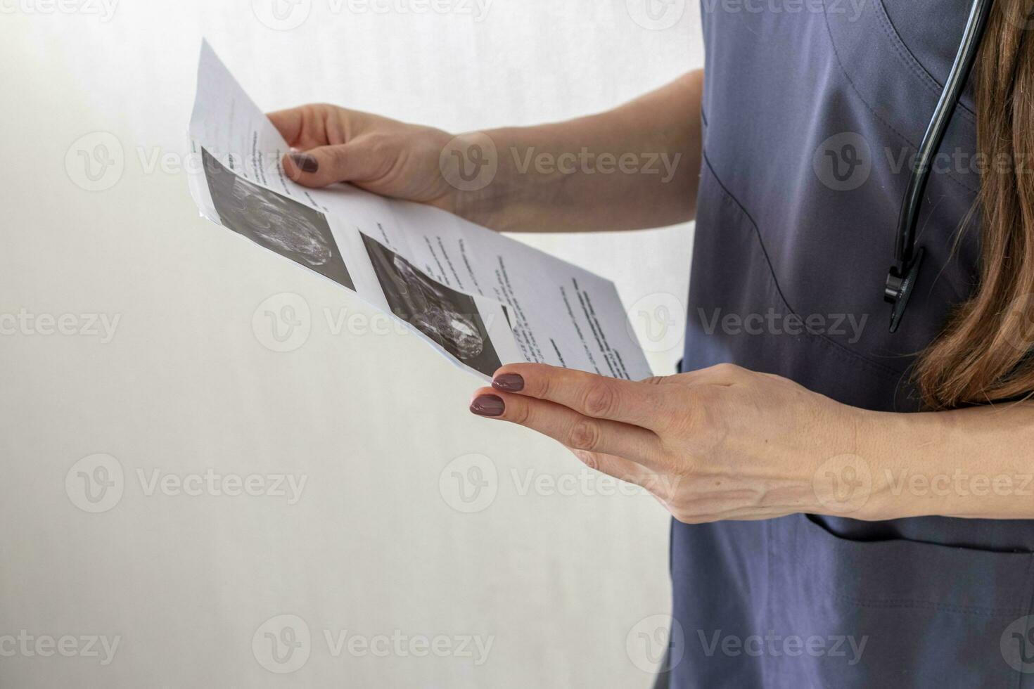 Shot of the female doctor in uniform against the white wall studying ultra sound image. Healthcare photo