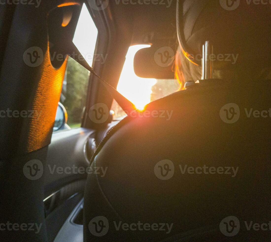 Young blonde woman driving the car towards the sunset. Concept photo
