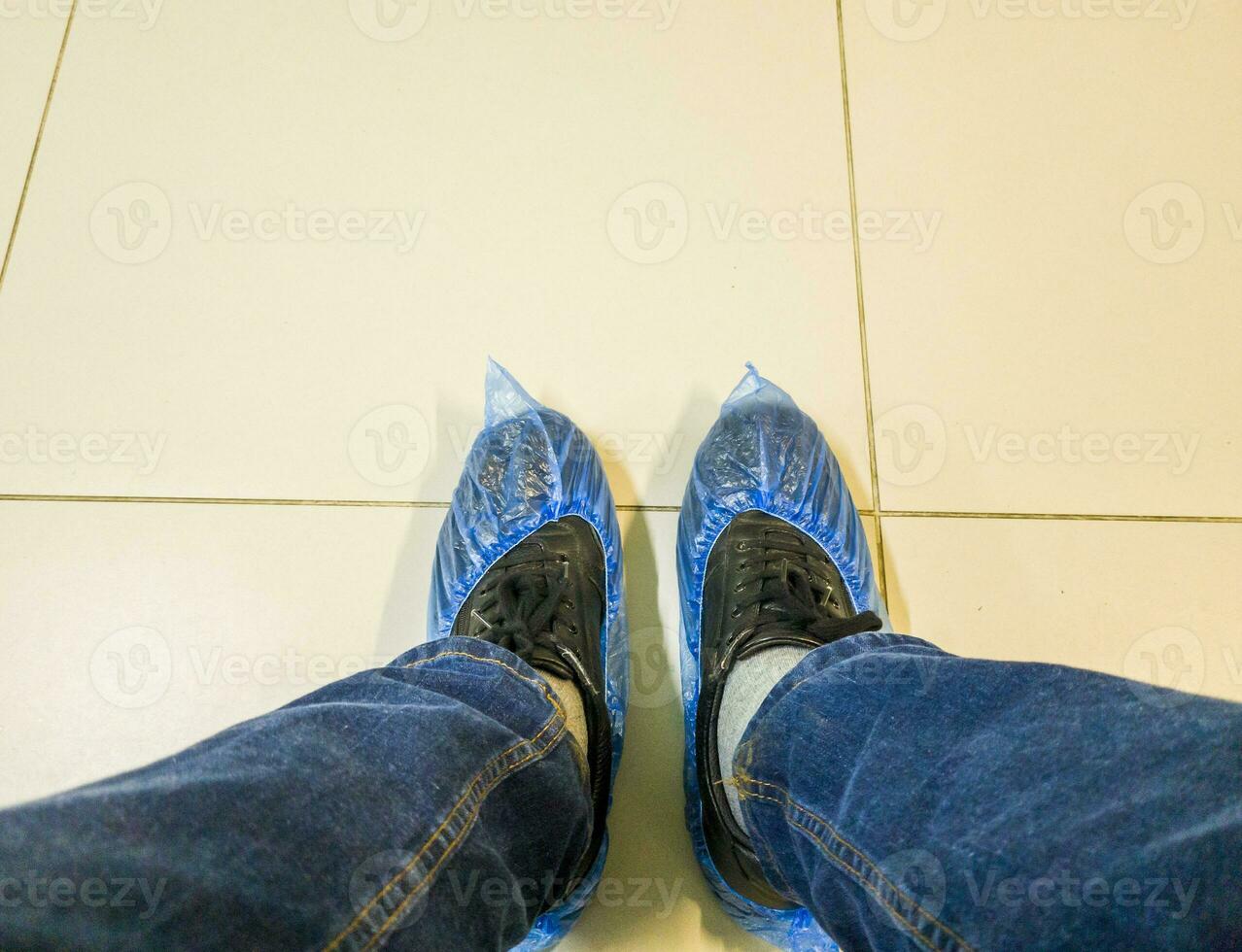 Person in the jeans wearing shoe covers in the clinic. Healthcare photo