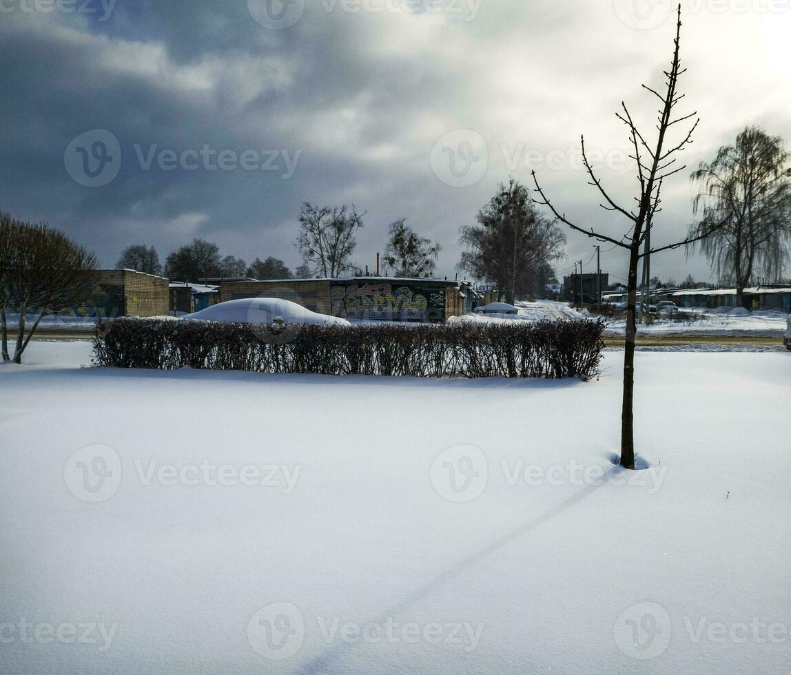 Landscape shot of the street on the winter day. Car covered in the snow. Season photo