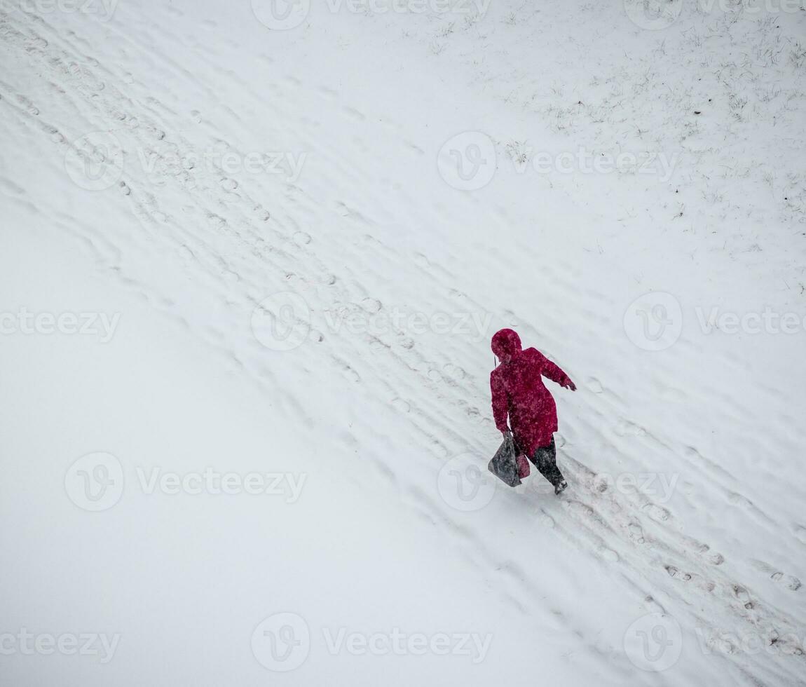 Shot of a woman in the red coat walking on the snow. Season photo