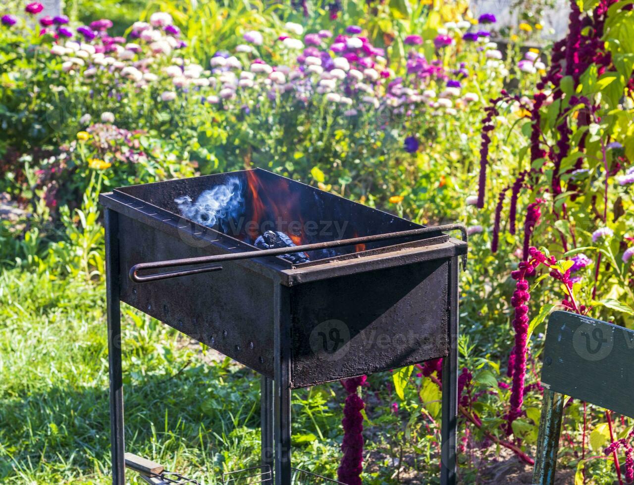 Close up shot of the grill with burning coals and wooden pieces. Outdoor photo