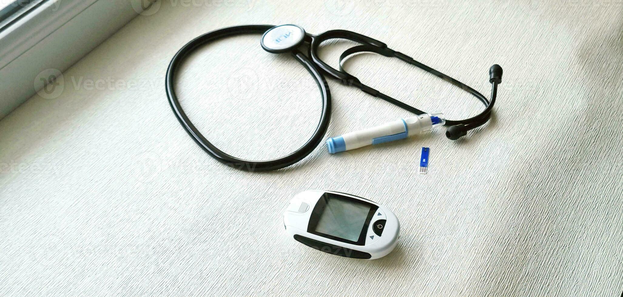 Close up shot of the glucometr instrument and stethoscope on the white surface. Healthcare photo