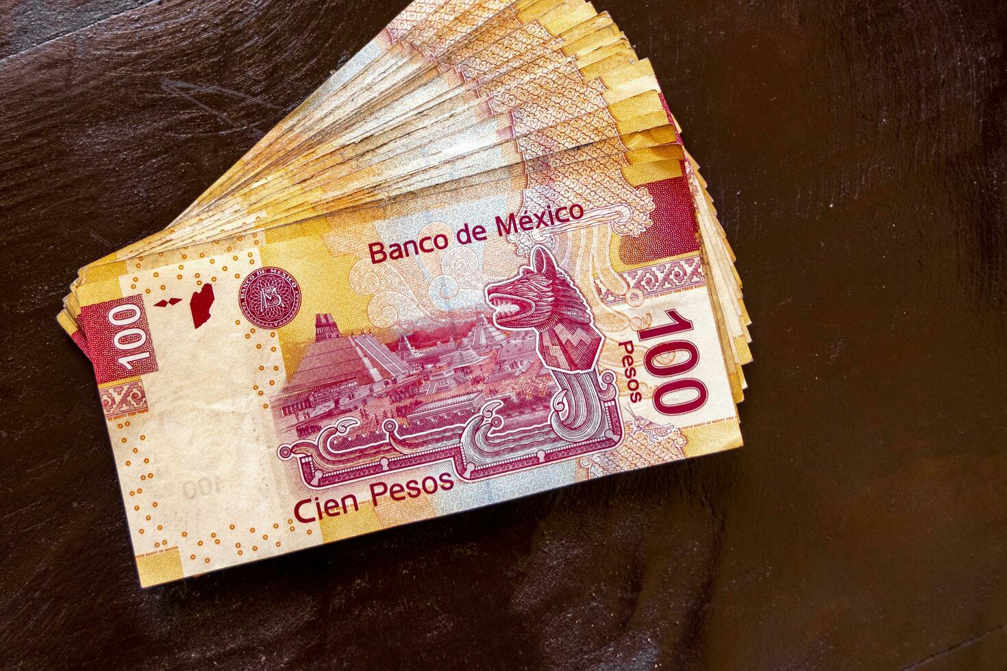 Playa del Carmen Quintana Roo Mexico 2021 Stack of banknotes 100 Mexican pesos on a wooden table. photo