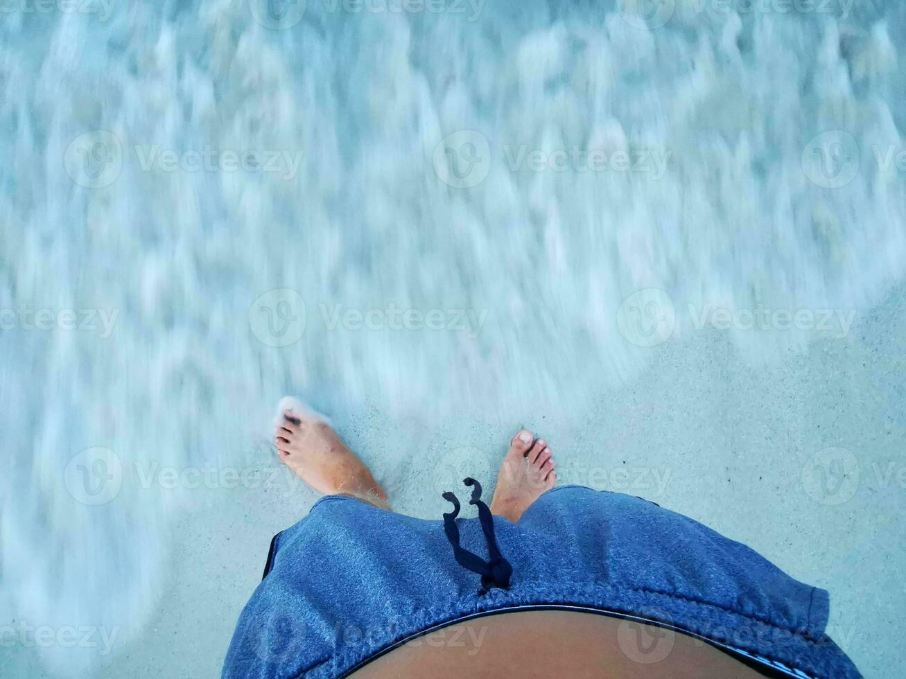 Feet of a man on beach sand and sea water. photo