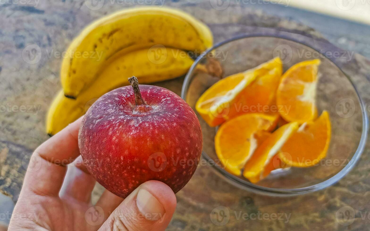 Bananas sliced oranges and red apple fruit on wooden table. photo