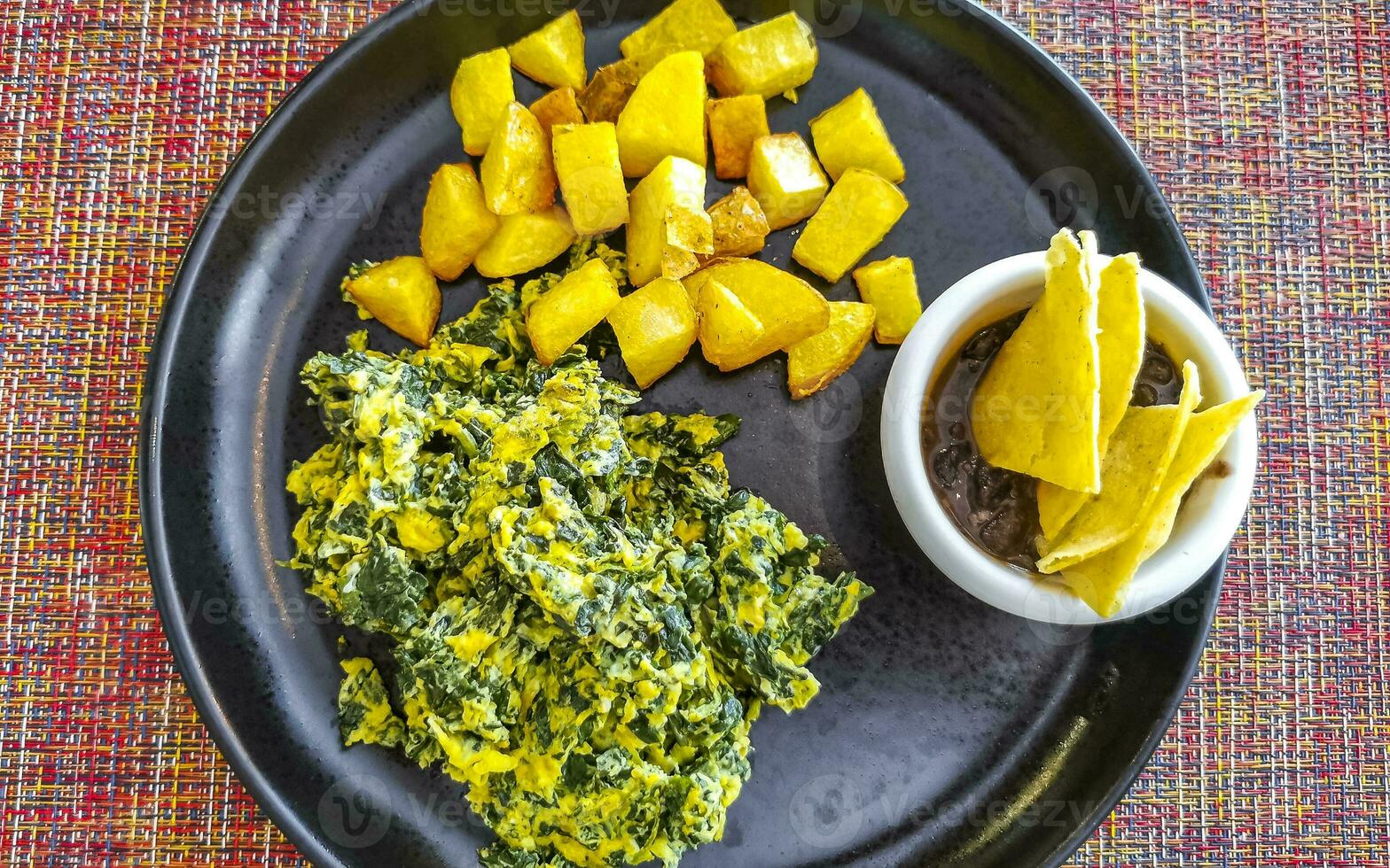 Breakfast scrambled eggs spinach fruit potatoes nicely arranged on plate. photo