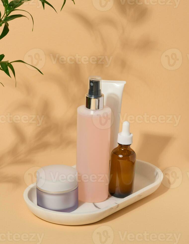 Set of facial care cosmetics on a beige background. Tonic, cream, lotion and oil photo