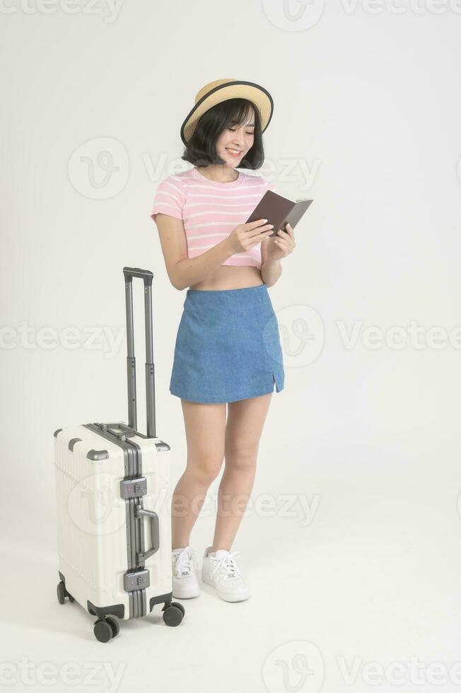 Young happy asian tourist woman over white background studio, travel and holidays concept. photo