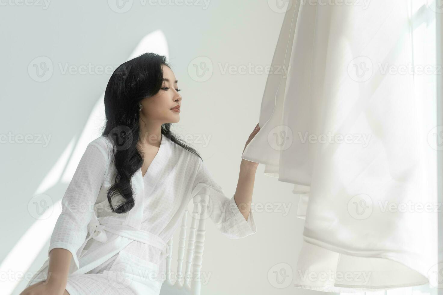 novia en blanco albornoz conmovedor y admirativo elegante Boda vestir preparando para Boda día, amor y matrimonio concepto foto