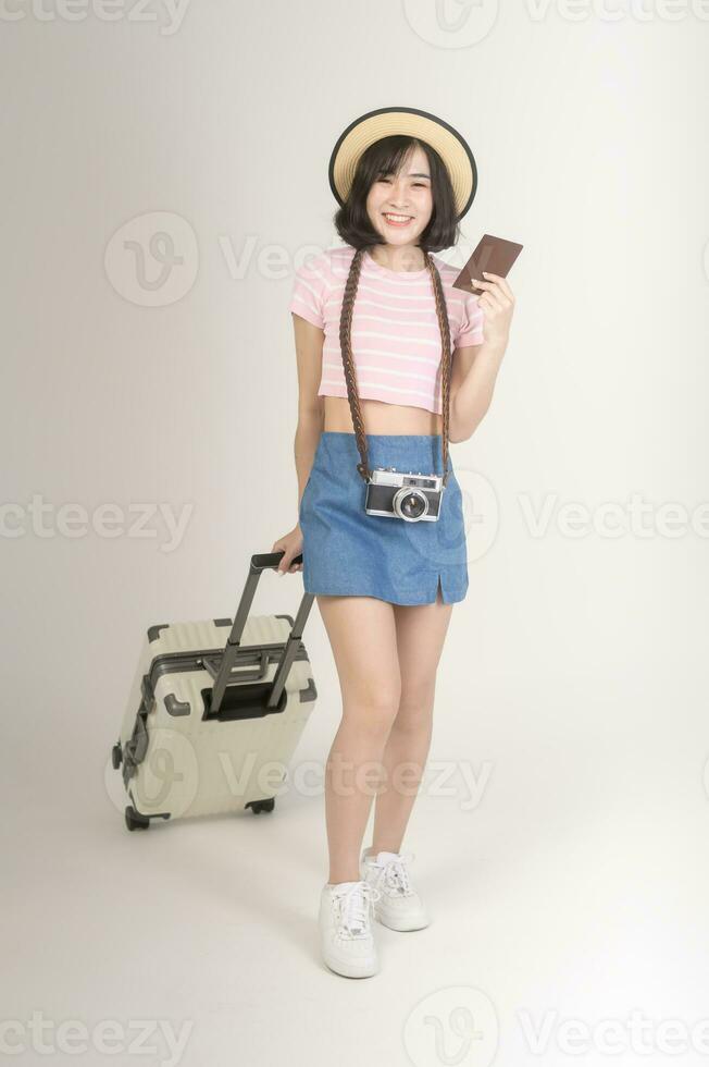 Young happy asian tourist woman over white background studio, travel and holidays concept. photo