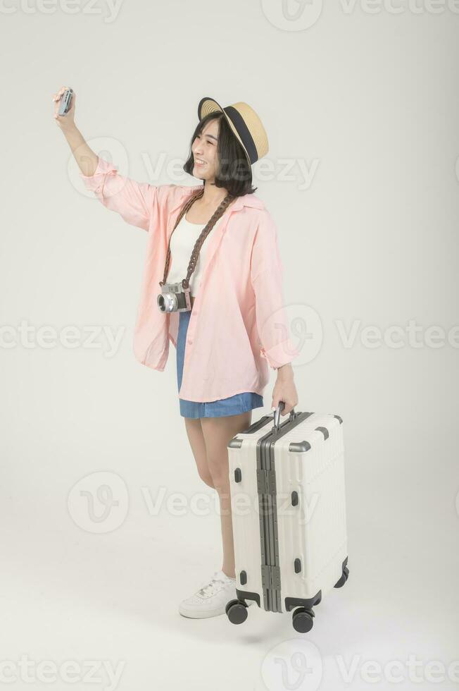 Young happy asian tourist woman over white background studio, travel and holidays concept. photo