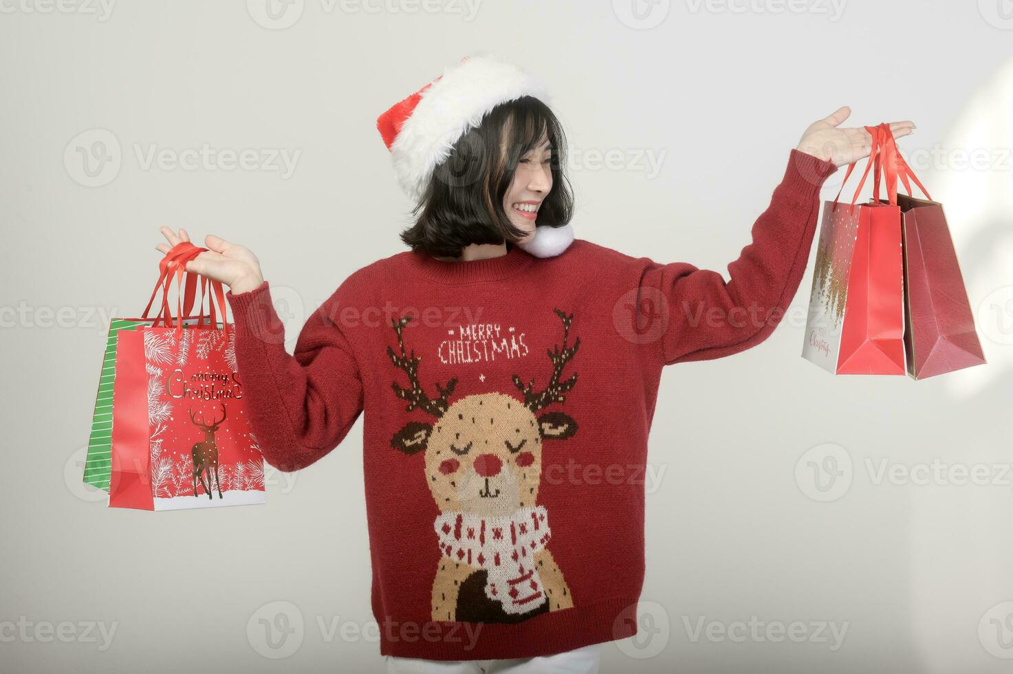 Young happy woman in santa claus hat wearing red sweater over white background, Christmas concept photo