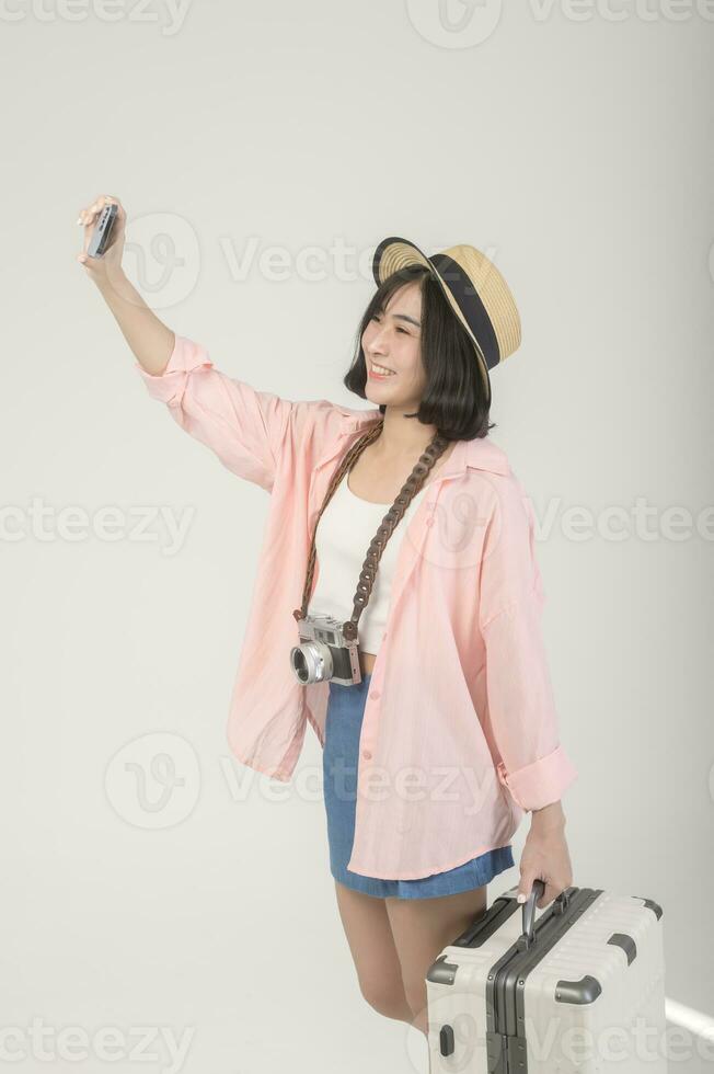 Young happy asian tourist woman over white background studio, travel and holidays concept. photo