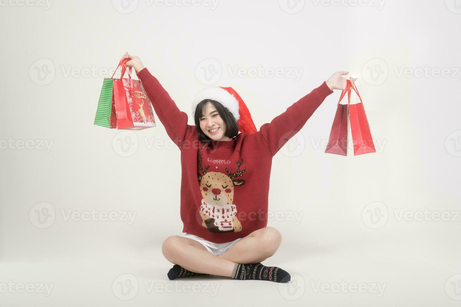 Young happy woman in santa claus hat wearing red sweater over white background, Christmas concept photo