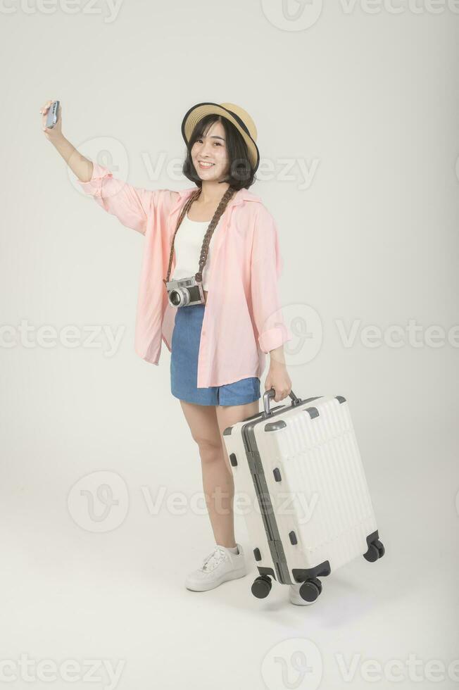 Young happy asian tourist woman over white background studio, travel and holidays concept. photo