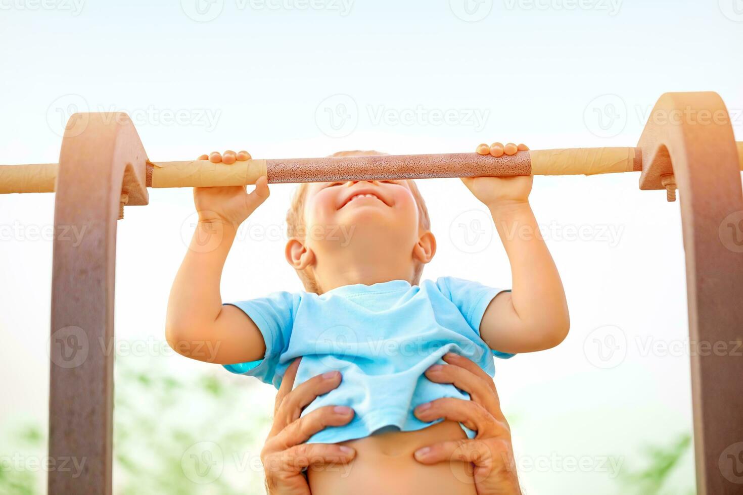 Little boy catch up on the horizontal bar photo