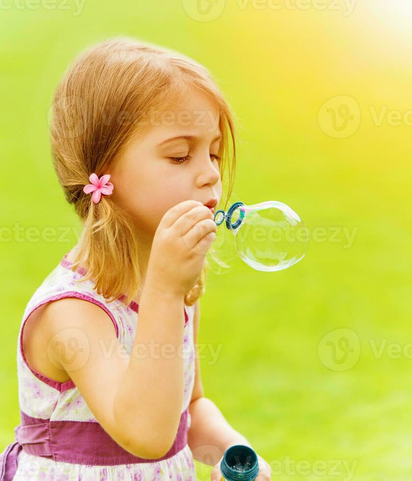 Baby girl blowing soap bubbles photo