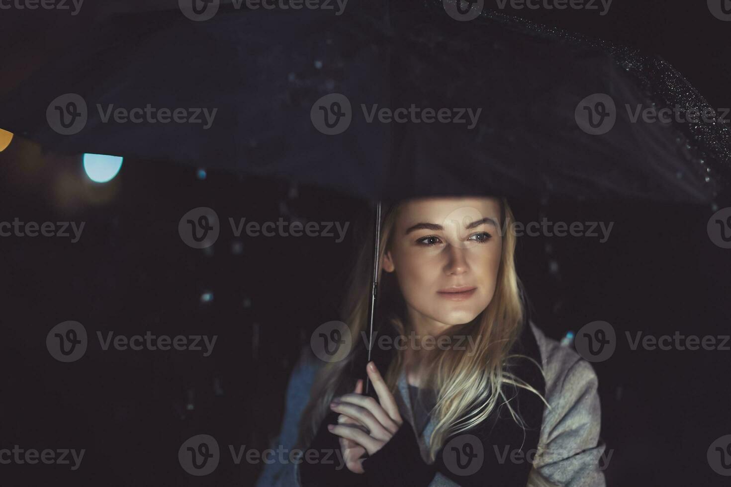 Thoughtful woman outdoors on rainy night photo