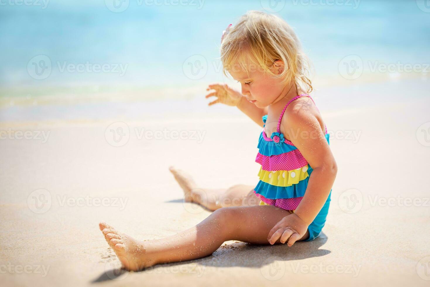 Baby girl playing on the beach photo