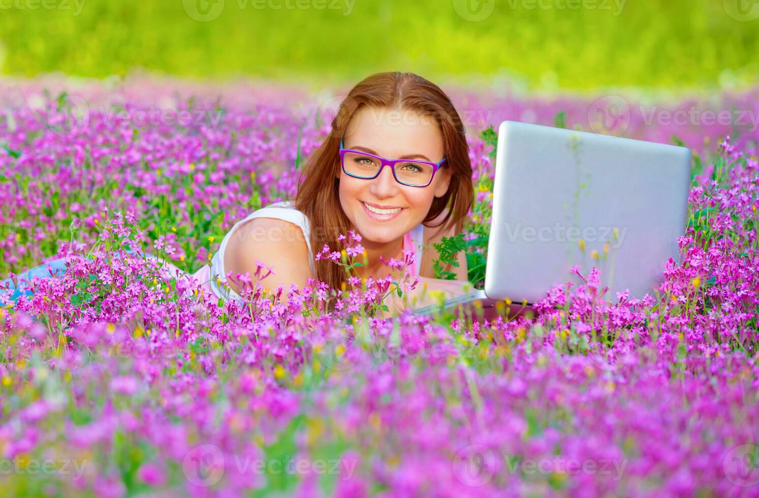 Pretty woman with laptop on floral field photo