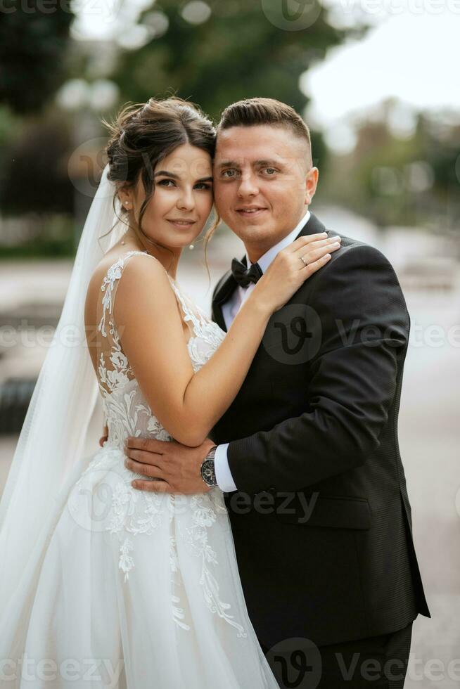 el novio con traje marrón y la novia con vestido blanco foto