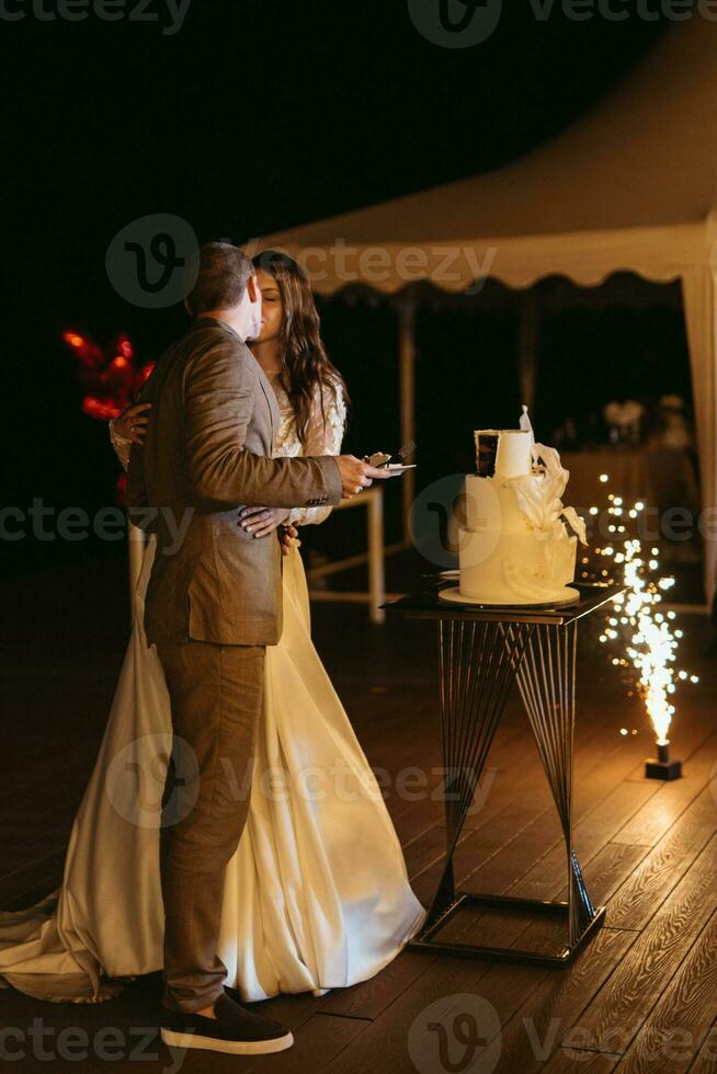 los recién casados felizmente cortan y prueban el pastel de bodas foto