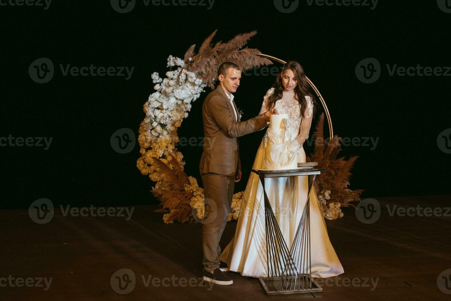 los recién casados felizmente cortan y prueban el pastel de bodas foto