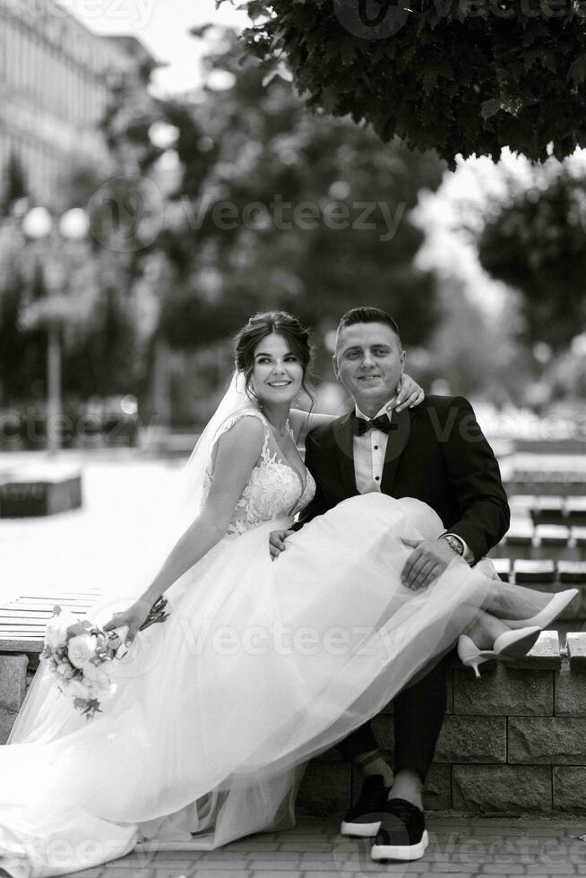 el novio con traje marrón y la novia con vestido blanco foto