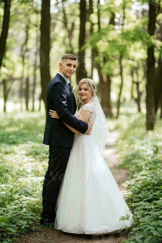 the groom and the bride are walking in the forest photo