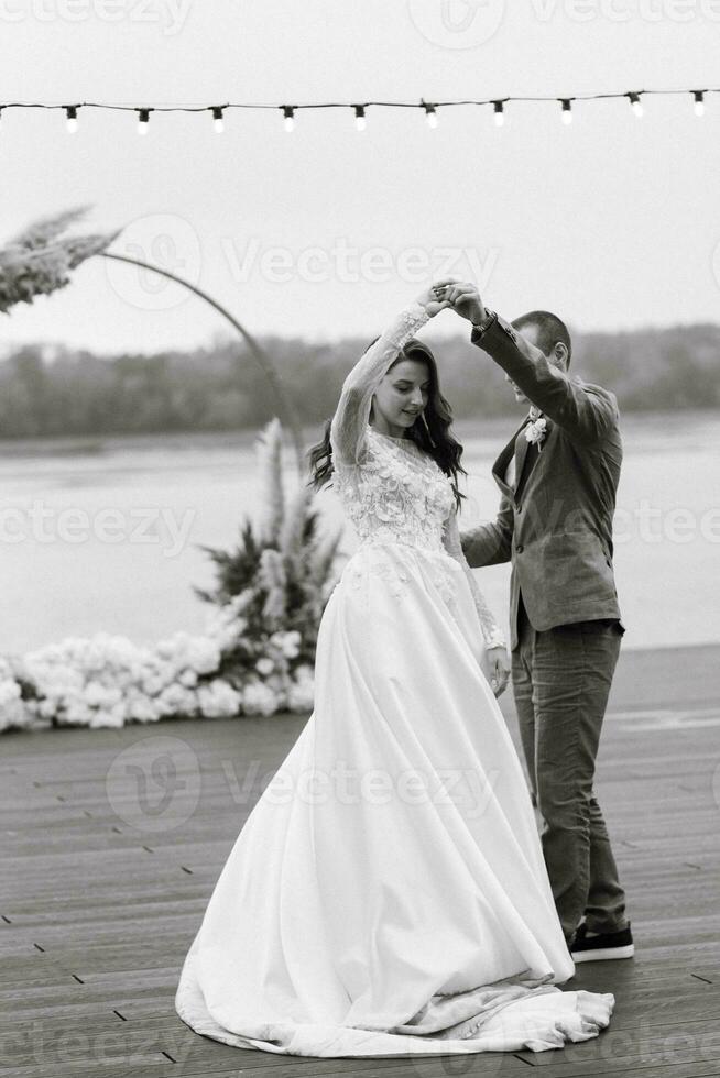 the first wedding dance of the bride and groom on the pier near the river photo