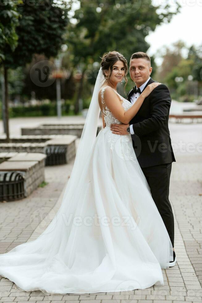 the groom in a brown suit and the bride in a white dress photo