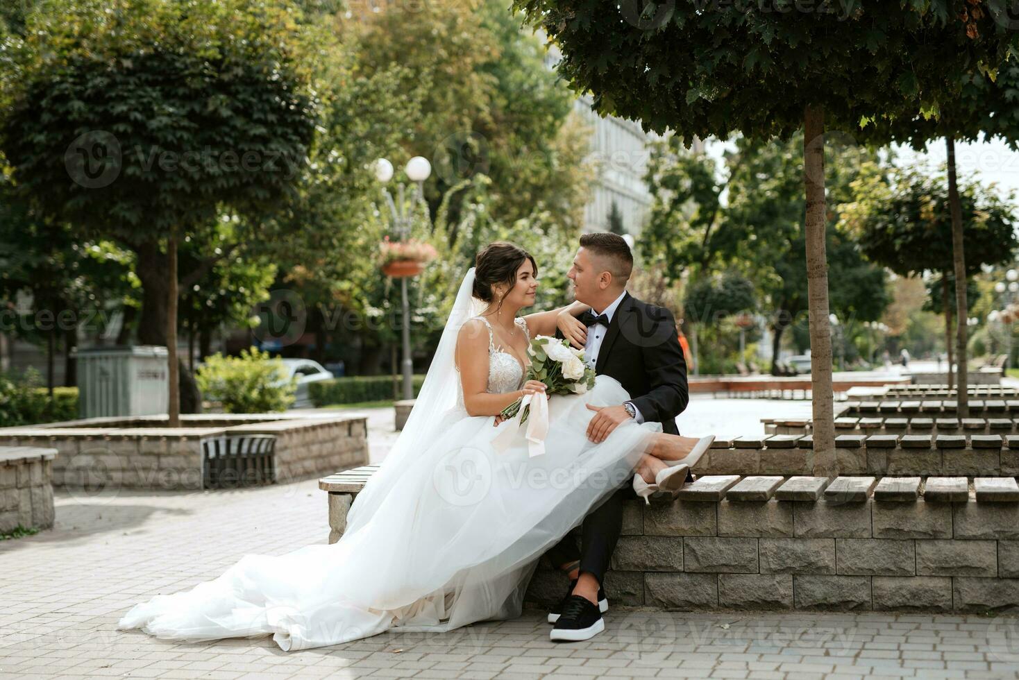 the groom in a brown suit and the bride in a white dress photo