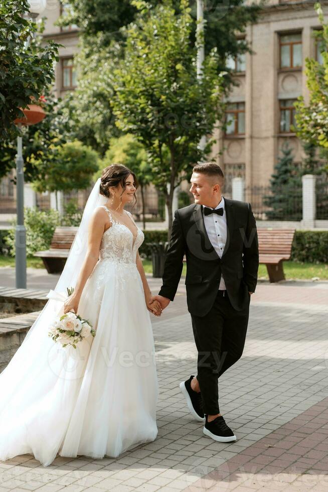el novio con traje marrón y la novia con vestido blanco foto
