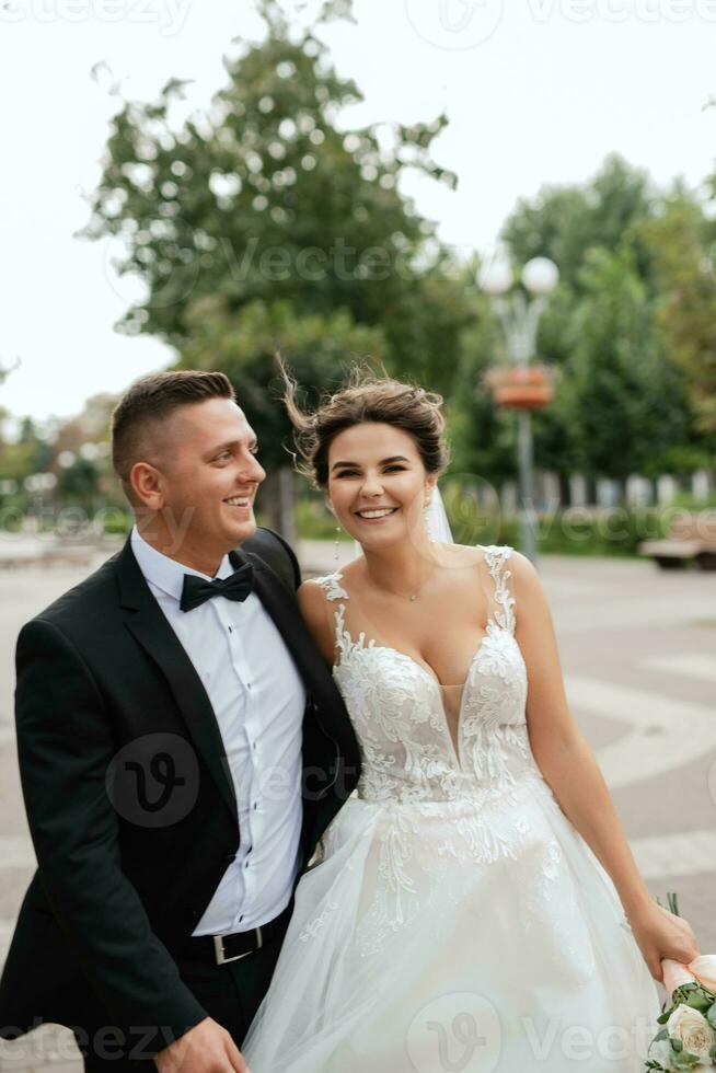 the groom in a brown suit and the bride in a white dress photo