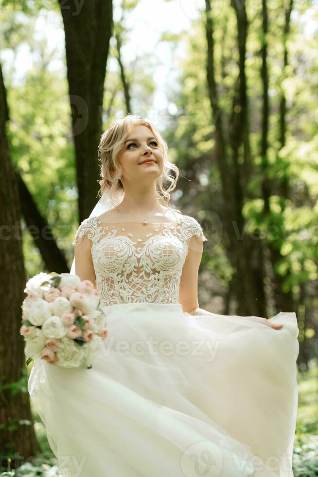 joven niña novia en un blanco vestir en un primavera bosque foto