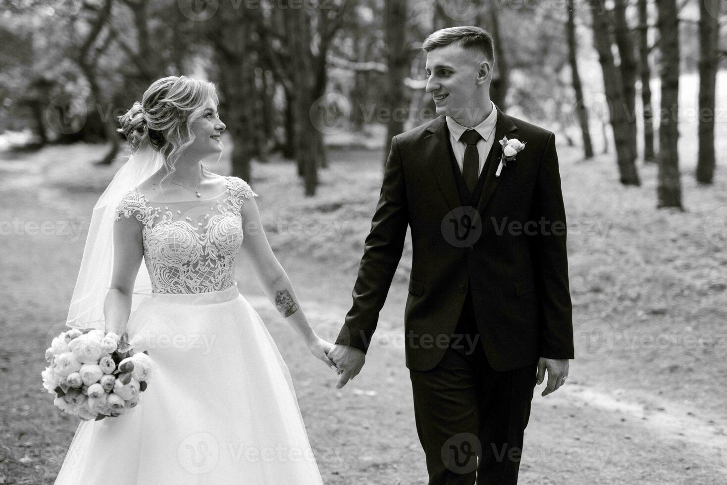 the groom and the bride are walking in the forest photo