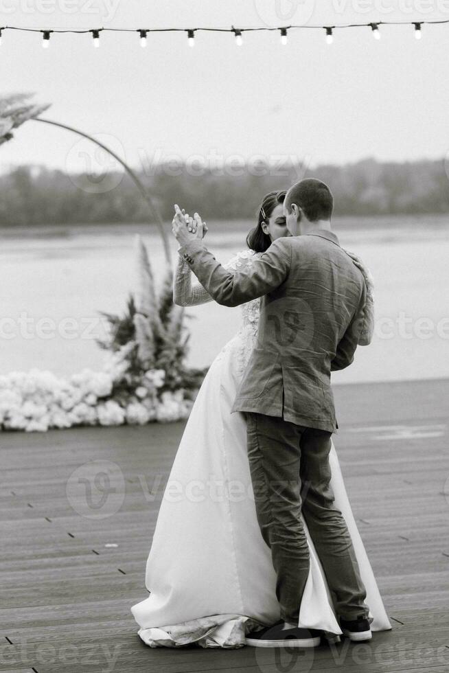 the first wedding dance of the bride and groom on the pier near the river photo