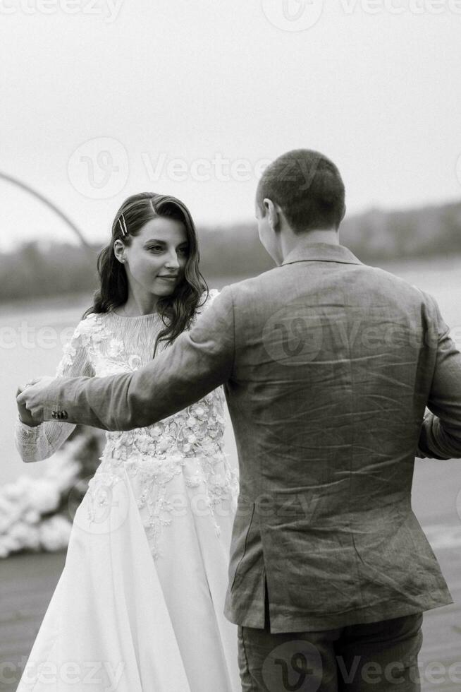 the first wedding dance of the bride and groom on the pier near the river photo