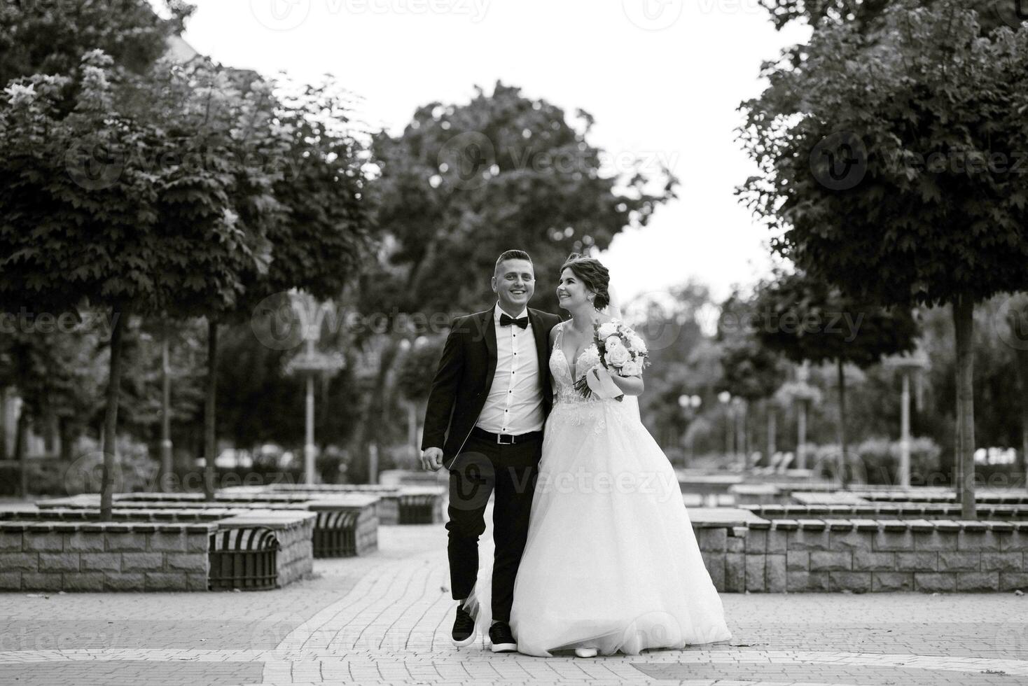 the groom in a brown suit and the bride in a white dress photo