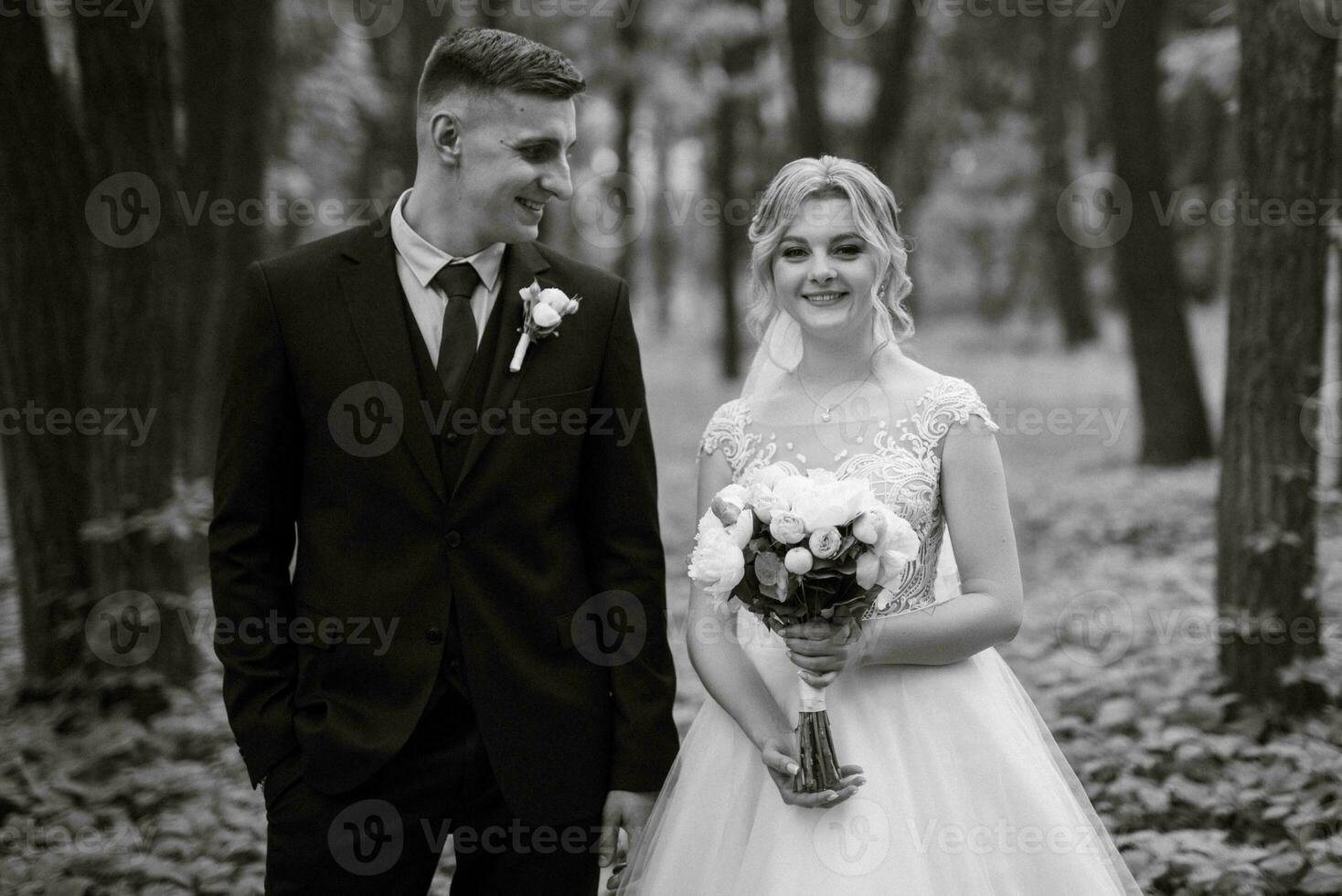 the groom and the bride are walking in the forest photo